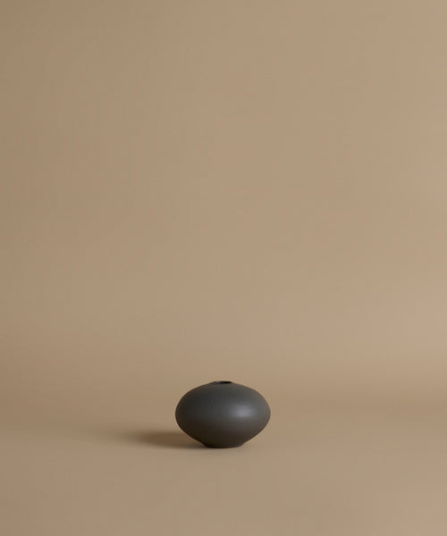 Black ceramic vase on a beige background