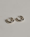 The Small Donut Hoops are chunky sterling silver earrings with clear backings, shown on a light gray textured surface.