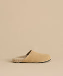 The Suede Ashby Clog features tan suede, a fluffy shearling-lined footbed, and a black sole, shown on a matching beige background.