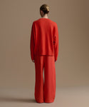 Woman wearing a red outfit against a beige background