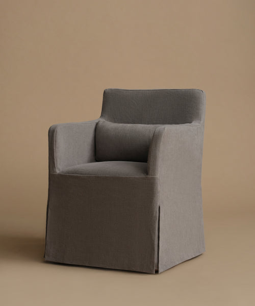A modern upholstered armchair with a high back and a matching back cushion, covered in a textured gray fabric, set against a solid warm beige background.