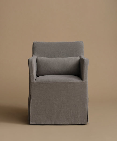 A modern gray upholstered armchair with a matching back cushion, set against a solid warm beige background.