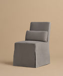 The Sunset Dining Chair features a modern, armless design with a straight back and seat, upholstered in gray fabric. Inspired by California design, it comes with a matching rectangular cushion on the backrest.