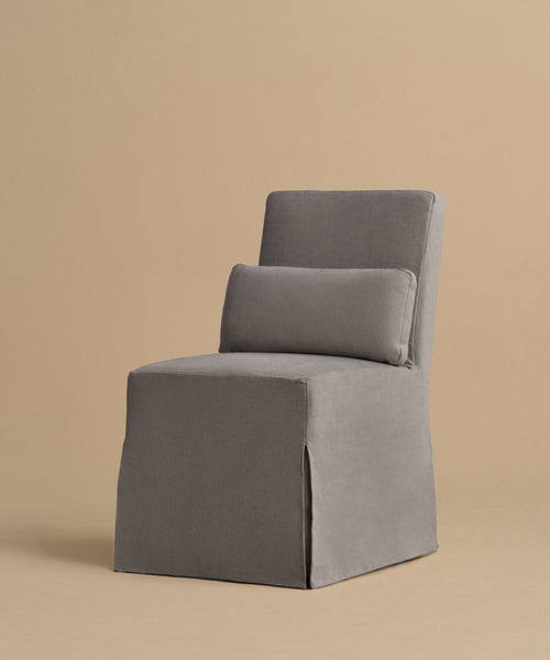 The Sunset Dining Chair features a modern, armless design with a straight back and seat, upholstered in gray fabric. Inspired by California design, it comes with a matching rectangular cushion on the backrest.