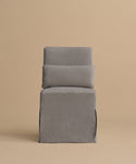 The Sunset Dining Chair, featuring a straight backrest and seat upholstered in light gray fabric, showcases modern California style against a plain beige background.