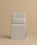 The Sunset Dining Chair is a minimalist, modern piece with light beige linen upholstery, a boxy base, rectangular backrest, and a matching cushion with removable slipcover, shown against a plain beige background.