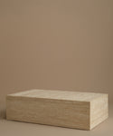A rectangle travertine coffee table against a beige background.