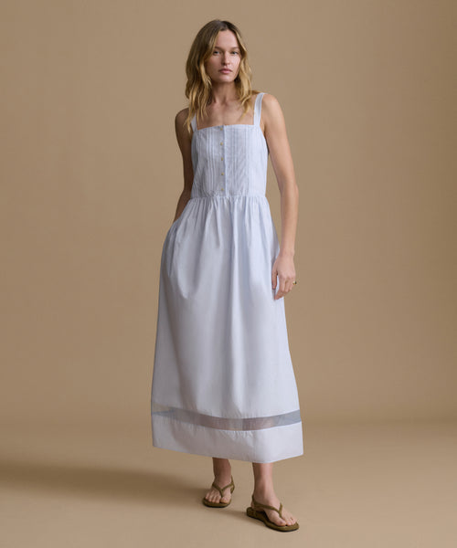 Woman wearing a light blue dress against a beige backdrop. 