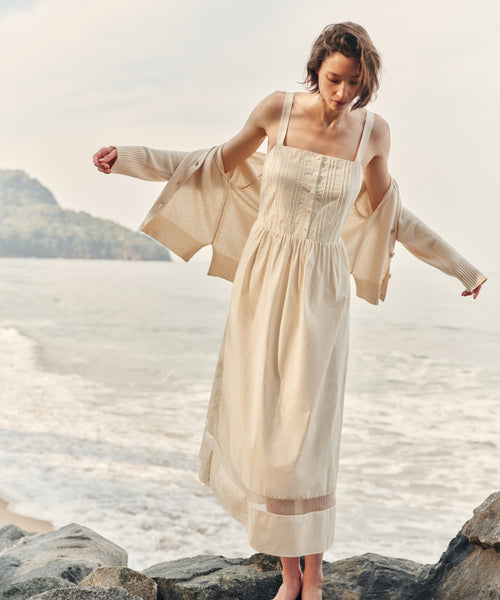 Woman wearing an ivory dress and cardigan at the beach.