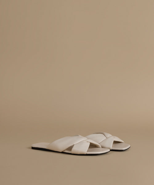 Pair of white sandals on a beige background