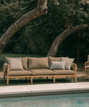 Outdoor sofa with cushions by a poolside in a garden setting