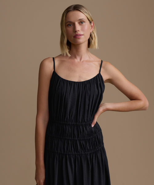Woman wearing a black wynn dress against a brown background