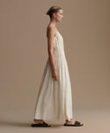 Woman wearing a long, cream wynn dress against a plain background