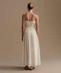 Woman wearing a long, cream wynn dress against a beige background