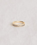 The Stevie Grey Diamond Band showcases a row of round-cut diamonds set along its gold band, beautifully displayed on a light, textured surface.