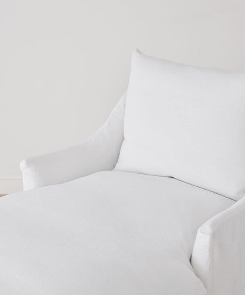 A close-up of the modern white Miramar Chaise, featuring a soft cushion and armrests, upholstered in Belgian linen, set against a plain white background.