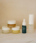 Five Oak Essentials’ Mini Routine features creams in glass jars, an oil with a dropper, and a pump—beautifully displayed on a light surface with a neutral background—making it the perfect travel companion.