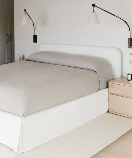 The Cove Bed features an upholstered headboard and comes dressed in ivory Belgian Libeco linen for a refined look, paired with a matching dresser.