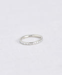 The Iris Eternity Band, inspired by Jenni Kayne, features small clear stones set in a delicate white gold band and is beautifully displayed on a white textured surface.
