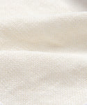 Close-up of the Cove Bed Slipcover, made from textured, off-white Belgian Libeco linen with a bumpy, pebble-like surface and soft folds.