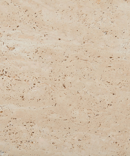 Close-up of the Sur Square Coffee Table’s light beige solid travertine surface, featuring natural holes, pores, and subtle variations in texture and color.