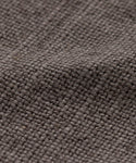 Close-up of the Sunset Dining Arm Chair Slipcover reveals its textured, brown burlap fabric with a coarse weave and grid-like pattern, providing a rustic, linen-like look with thick threads across the surface.