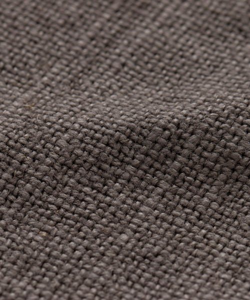 Close-up of the Sunset Dining Arm Chair Slipcover reveals its textured, brown burlap fabric with a coarse weave and grid-like pattern, providing a rustic, linen-like look with thick threads across the surface.
